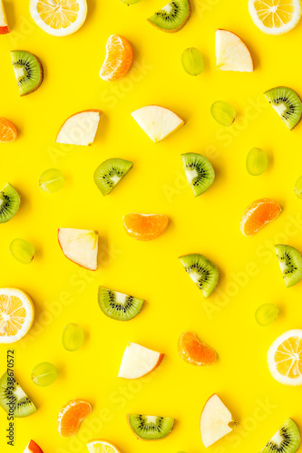 Colorful fruit pattern with citrus and kiwi slices - fresh summer fruits - on yellow background top-down