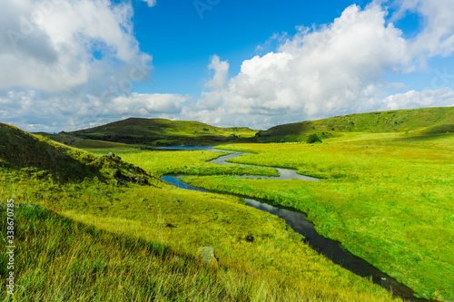 amazing landscape in the countryside with a stream flowing by and a vista view of the clouds and the mountains