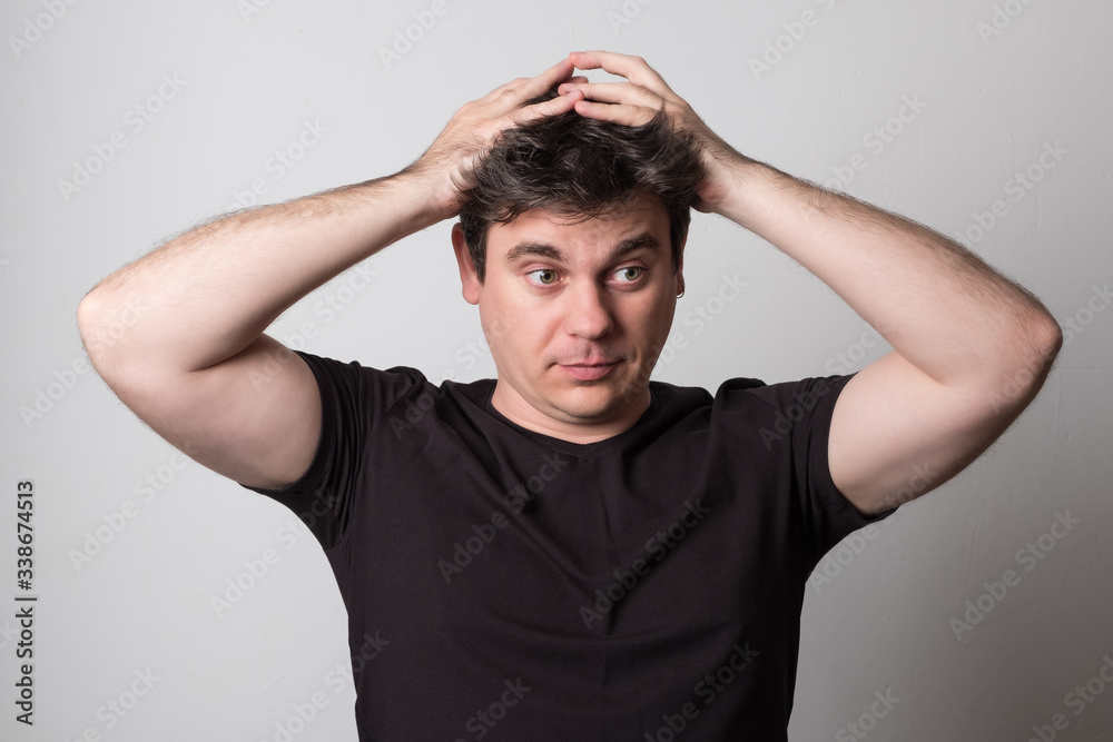 Sad man in a black t-shirt. Young man with beautiful hair. Studio image. Sad man in a black t-shirt. Young man with beautiful hair. Studio image.