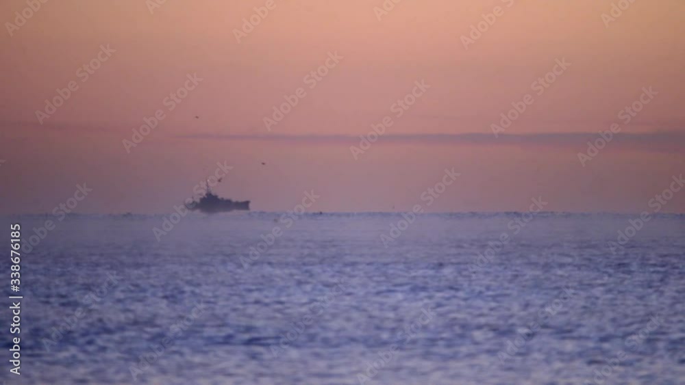 Fishing Boat Sailing on Horizon During Sunrise With Birds Flying off The Coast of Cornwall, England Fishing Boat Sailing on Horizon During Sunrise With Birds Flying off The Coast of Cornwall, England
