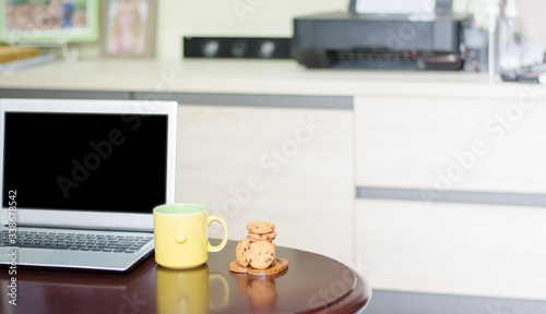 Hot coffee with a laptop and dessert cookies on a wooden table, working at home during the quarantine for the virus. C0vid-19