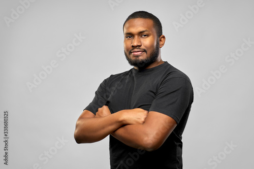 people concept - young african american man in black t-shirt with crossed arms over grey background photo