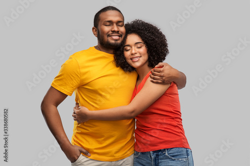relationships and people concept - happy african american couple hugging over grey background