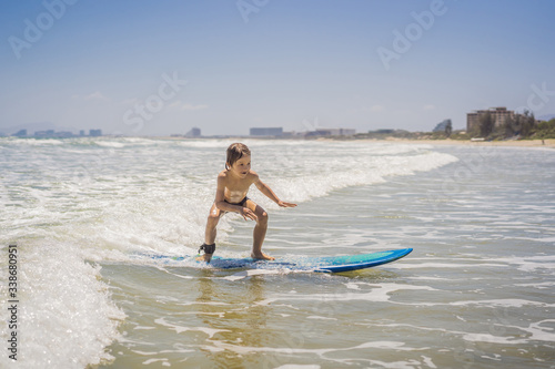 Healthy young boy learning to surf in the sea or ocean