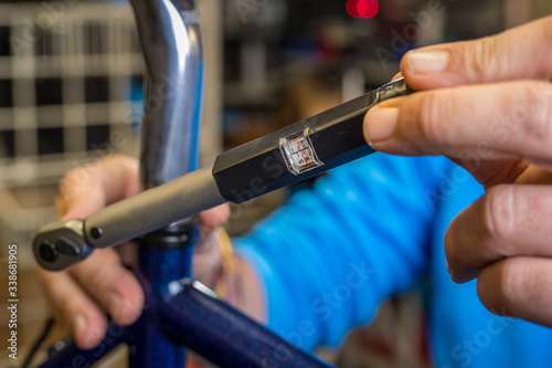 Tightening of a bicycle seat post with the use of a small torque wrench. Proper way to tighten a bicycle seatpost. Bicycle service in a worshop. photo