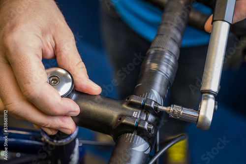 Tightening of a bicycle handlebar stem with the use of a small torque wrench. Proper way to tighten a bicycle handlebars. Bicycle service in a worshop. photo