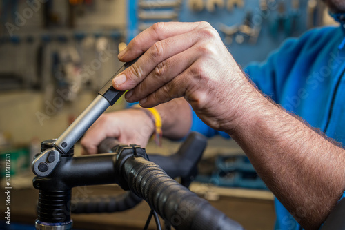 Tightening of a bicycle handlebar stem with the use of a small torque wrench. Proper way to tighten a bicycle stem. Bicycle service in a worshop. © Anze