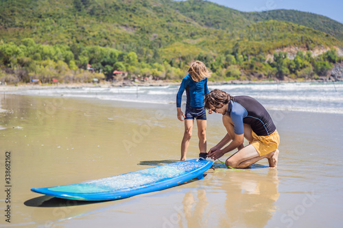 Father or instructor teaching his son how to surf in the sea on vacation or holiday. Travel and sports with children concept. Surfing lesson for kids