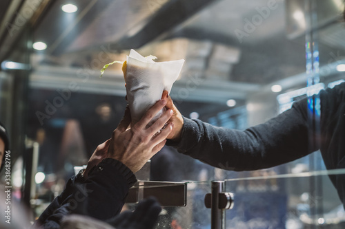 Canvas Print Person receiving a fresh kebab or gyros in a fast food stall or vendor outside in a city