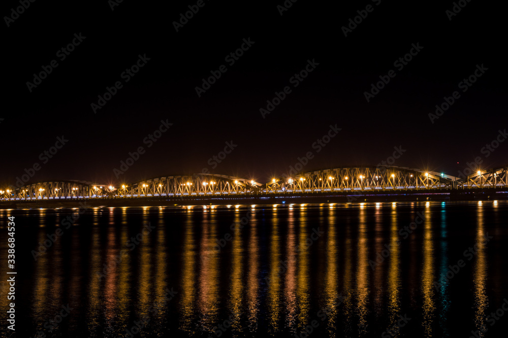 Faidherbe bridge, a metal bridge spaning over the river in Sant Louis, Senegal in late night with a cars and some people passing over it.