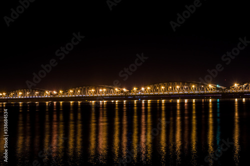 Faidherbe bridge, a metal bridge spaning over the river in Sant Louis, Senegal in late night with a cars and some people passing over it. © Anze
