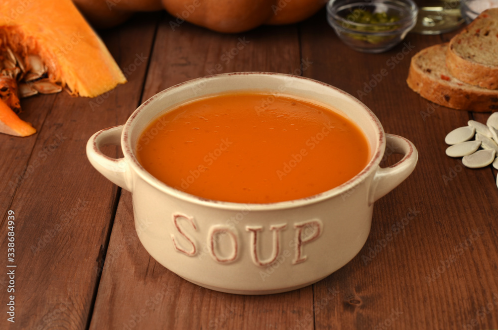 Roasted pumpkin and carrot soup with ingredients on rustic wooden background. Natural organic vegetable pumpkin, carrot bread, salt, oil and seed on background. Roasted pumpkin and carrot soup with ingredients on rustic wooden background. Natural organic vegetable pumpkin, carrot bread, salt, oil and seed on background.