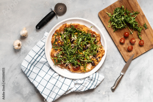Vegan pizza with vegetables and arugula.