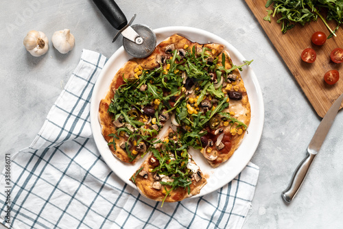 Vegan pizza with vegetables and arugula.