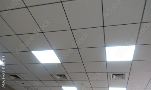 White calcium silicate Square Grid suspended false ceiling work for an office in an high rise buildings for large office spaces with LED lighting for better reflection photo