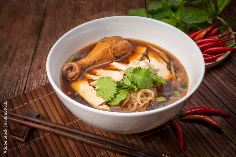 Chicken noodle soup on wood table, Chicken soup with noodles and vegetables in bowl over rustic wooden background Chicken noodle soup on wood table, Chicken soup with noodles and vegetables in bowl over rustic wooden background