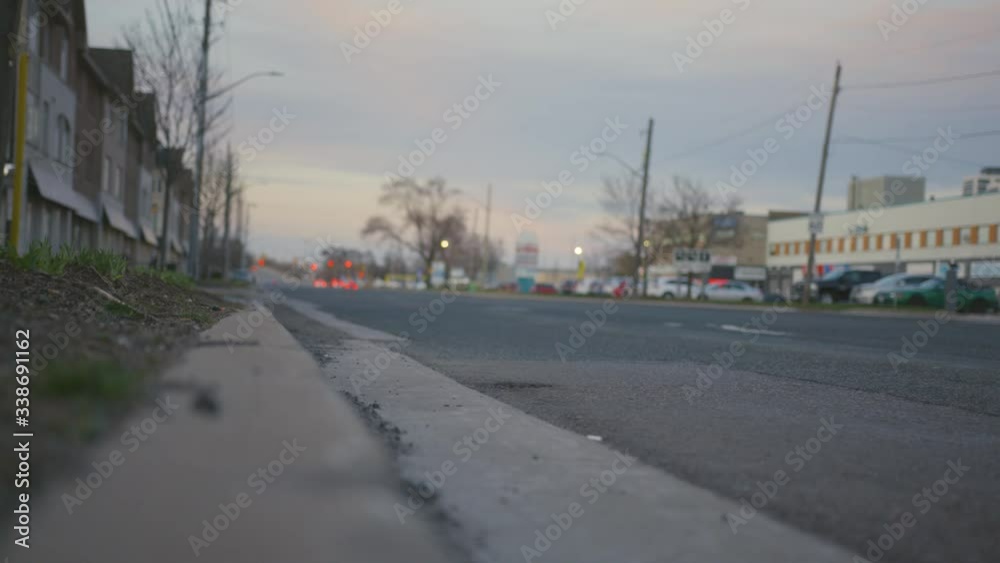 Nearly empty road at dusk in industrial area. Single SUV drives past camera.