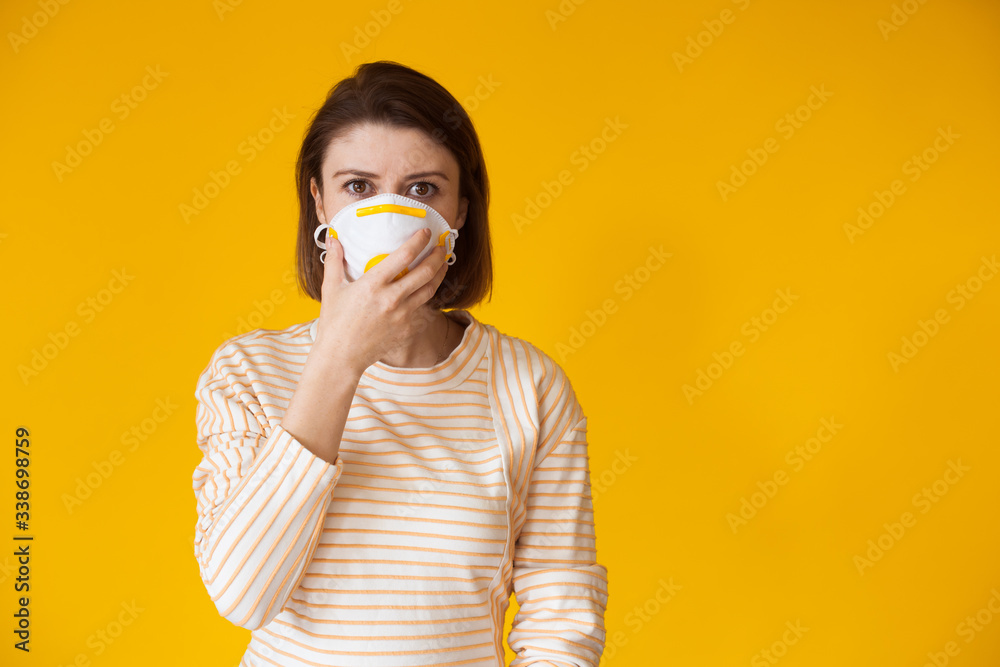 Caucasian lady posing on a yellow background with free space while wearing a mask with filter Caucasian lady posing on a yellow background with free space while wearing a mask with filter