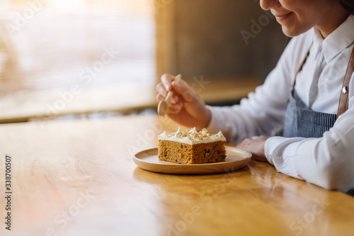 A beautiful female chef baking and eating a piece of homemade carrot cake in wooden tray