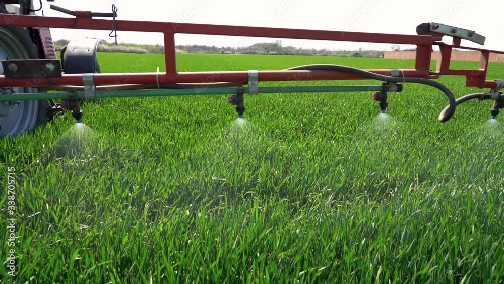 Farming Tractor Spraying Green Wheat Field in Slow Motion