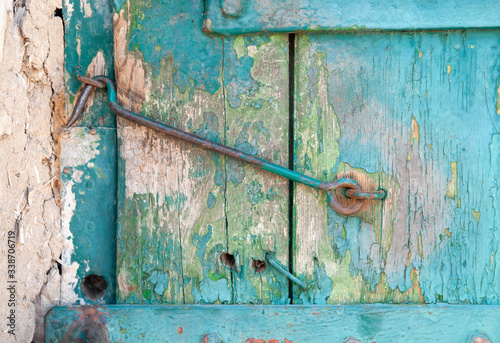 The closed door is locked, the old hook on the wooden door with which the paint peeled off
