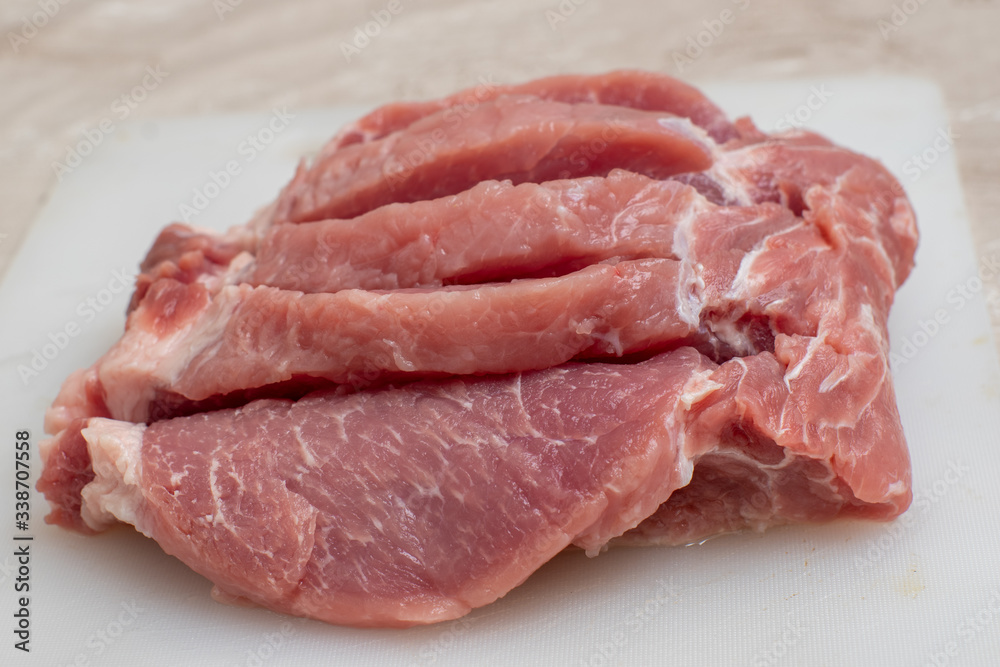 Close-up of several steaks, pieces of pork on a white cutting board Close-up of several steaks, pieces of pork on a white cutting board