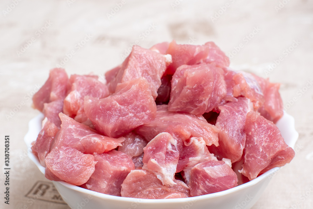 Close up sliced raw meat in a white bowl on a light table Close up sliced raw meat in a white bowl on a light table