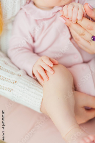 Close-up. Beautiful young mother holds the hands of her little daughter. Baby. Newborn.