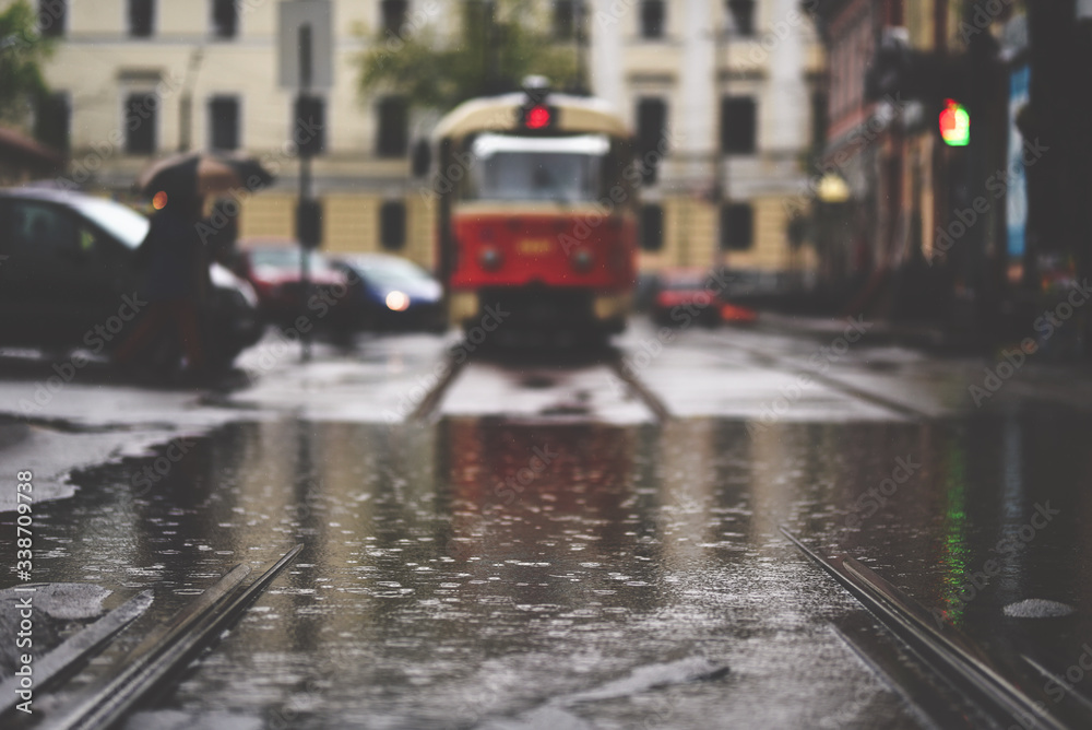 Scene of rainy european city in retro style. Selective focus on puddle and tram on background. Location - Square of Contracts (Kiev)