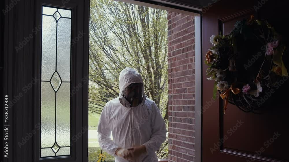man in PPE gear entering home in pandemic man in PPE gear entering home in pandemic