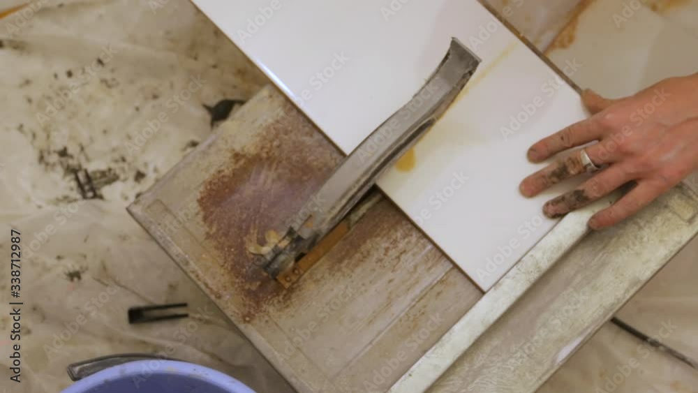 Worker cutting tiles on tile cutter