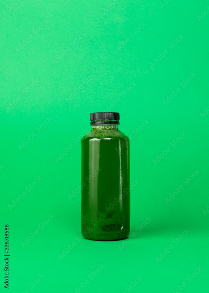 Fresh celery spinach juice in a plastic bottle isolated on green background. Healthy eating Detox juice diet.