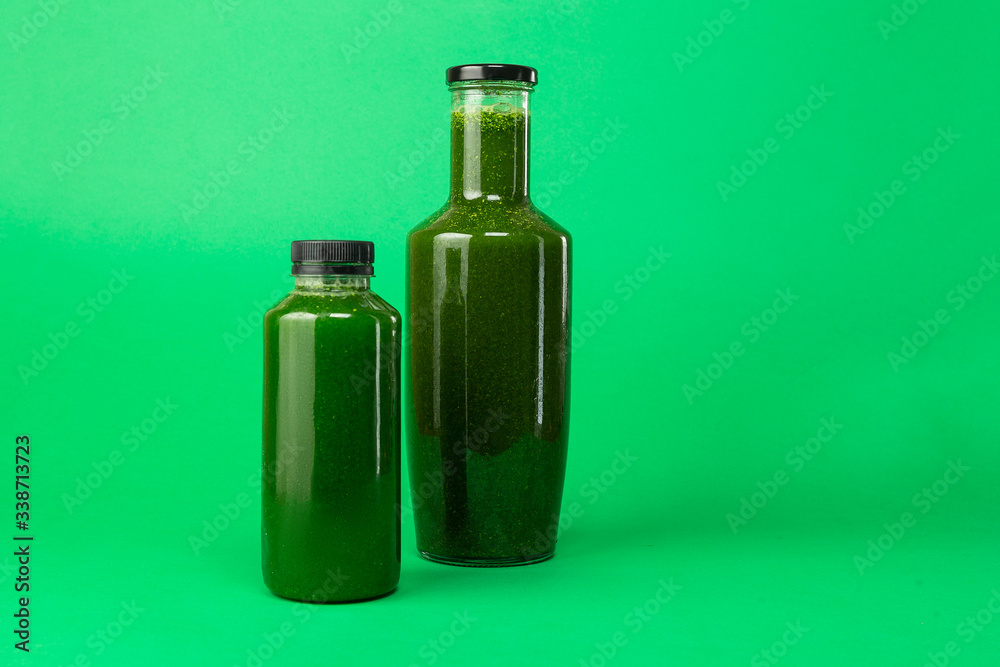 Fresh celery spinach juice in a plastic and glass bottle, isolated on a green background. Healthy diet detox juice. Fresh celery spinach juice in a plastic and glass bottle, isolated on a green background. Healthy diet detox juice.