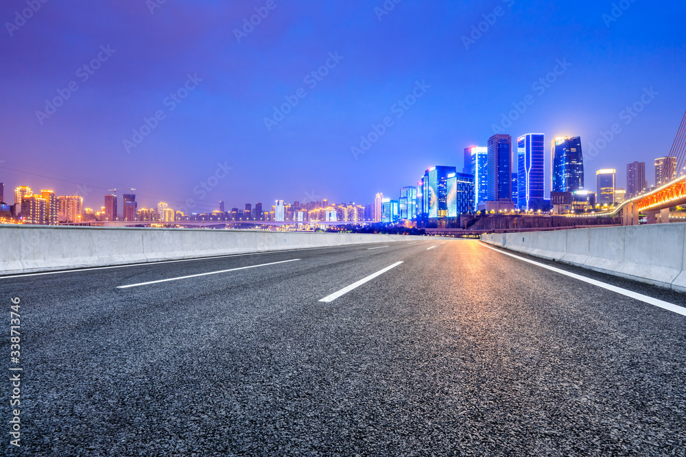Empty asphalt road and city skyline with commercial buildings at night in Chongqing,China.