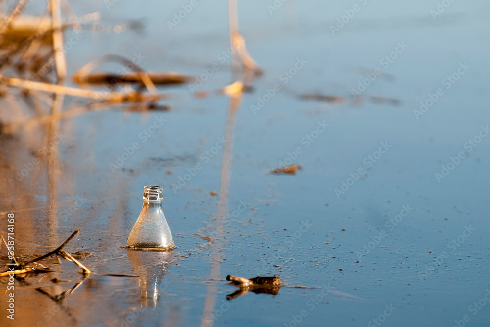 Naklejka premium Old plastic bottle floating in water. Environmental pollution. The fight against economic crimes