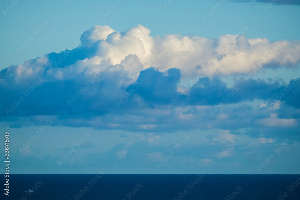 Beautiful blue coloured background of sea ocean water and horizon line with white clouds in the sky - concept of travel and nature