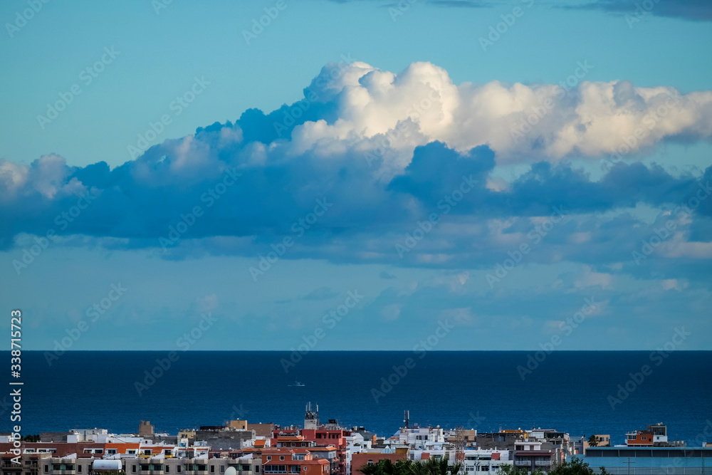 Beautiful blue coloured background of sea ocean water and horizon line with white clouds in the sky and coloured houses on the town coast - concept of travel tourism and nature