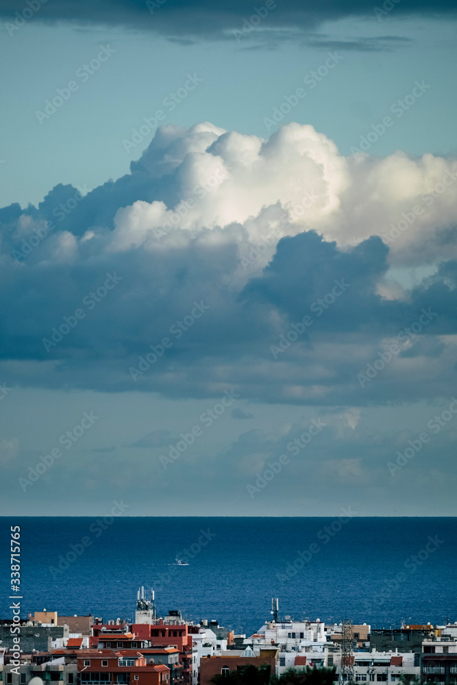 Beautiful blue coloured background of sea ocean water and horizon line with white clouds in the sky and coloured houses on the town coast - concept of travel tourism and nature
