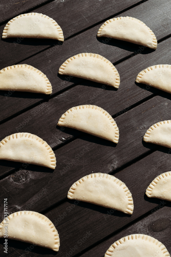 Raw dumplings on black wooden background. Natural homemade food.