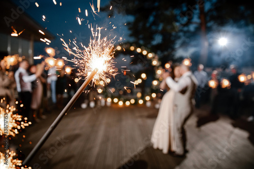 Sparkler in hands on a wedding - bride, groom and guests holding lights