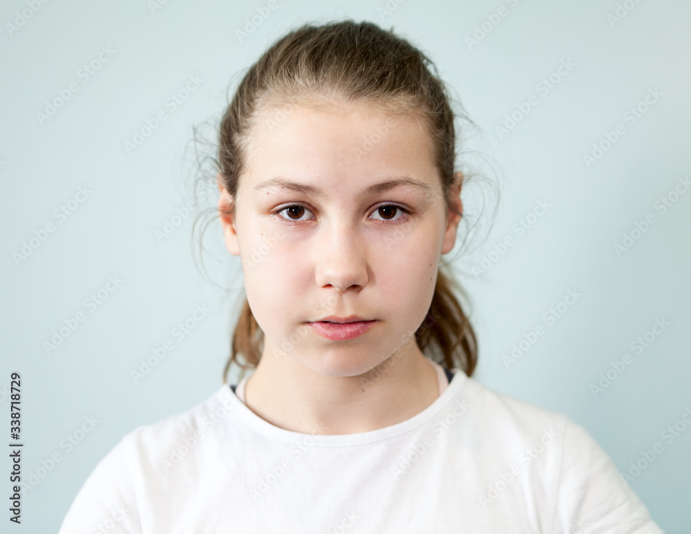 Young Caucasian girl with a neutral expression on her face. Portrait on grey background, emotions series Young Caucasian girl with a neutral expression on her face. Portrait on grey background, emotions series