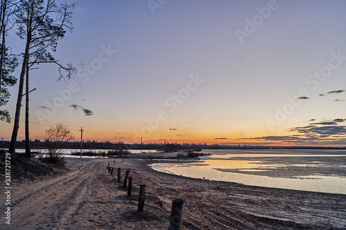 autumn landscape. sandy road between lakes at sunset