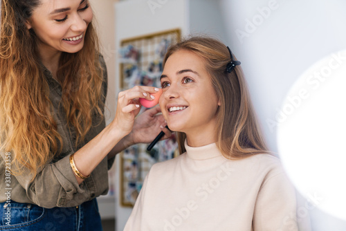 Beauitufl smiling young woman getting her makeup done