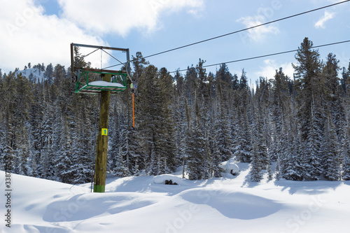 Fototapeta Naklejka Na Ścianę i Meble -  Empty surface lift on a ski slope among pure snow and coniferous forest. Active winter leisure and ski resort concept. Snowy backcountry ski slopes scenery