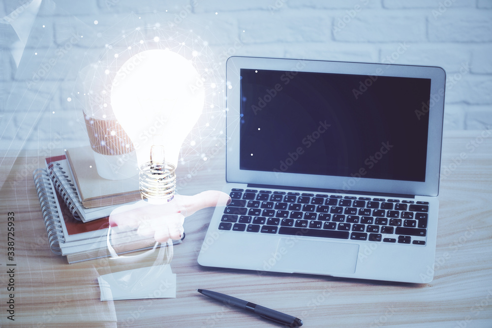 Computer on desktop in office with bulb icon hologram. Multi exposure. Concept of idea. Computer on desktop in office with bulb icon hologram. Multi exposure. Concept of idea.