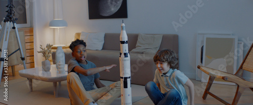 African American and Caucasian classmates friends working on a moon landing homework project rocket model. Smart, science, dreamer kids photo