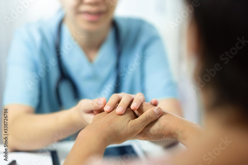 Asian medical nurse talking and comforting senior woman patient in office room. Female elderly Being reassured by Physician with holding hands © eggeeggjiew