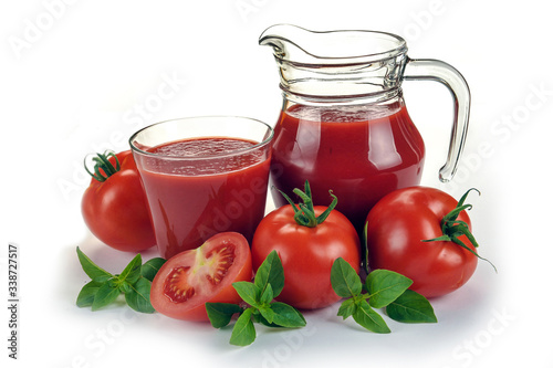 Fresh red tomatoes in basket and tomato juice in glass and jug on white