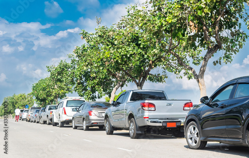 Cars parked in a row on street side under trees. business cars parking on road side © merrymuuu