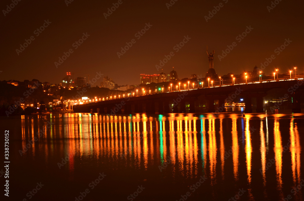 Kyiv city, the capital of Ukraine at night beside the Dnipro river with reflection in water